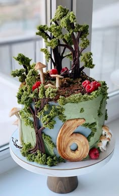 a cake decorated with trees and mushrooms on top of a table next to a window