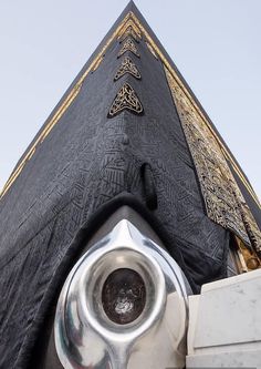 the top of a building with an ornate design on it's side and a metal object in front of it