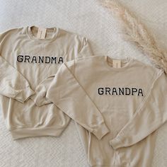 two sweaters with the words grandma and grandpa on them are laying on a bed