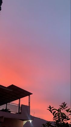 the sky is pink and purple as the sun sets over a building with balconies