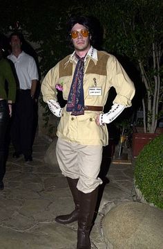 a man dressed in costume standing on a stone walkway at night with sunglasses on his face