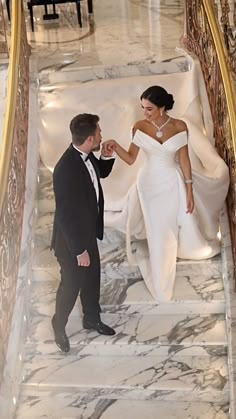 a bride and groom walking down the stairs at their wedding ceremony in an elegant building