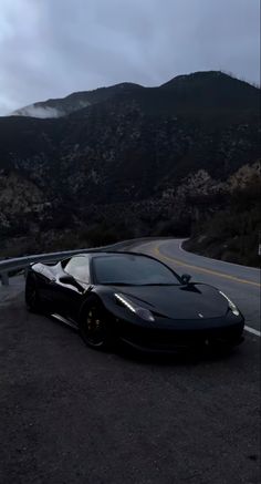 a black sports car parked in front of a mountain