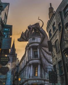 a large building with a dragon statue on top of it's roof next to tall buildings