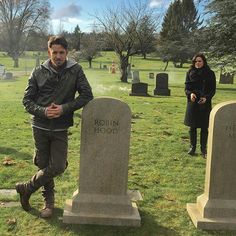 two people standing next to headstones in a cemetery