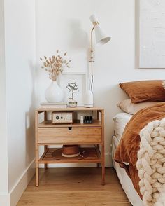 a bed room with a neatly made bed and a night stand next to the bed