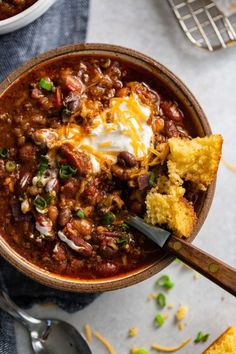 a bowl filled with chili and cornbreads on top of a table