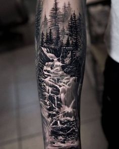 a man's arm with a black and white landscape tattoo on it