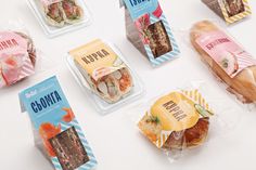 several different types of sandwiches in plastic wrappers on a white table with pink and blue stripes