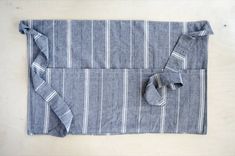 a blue and white striped placemat with folded napkins on the edge, sitting on top of a wooden table