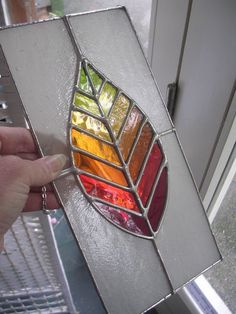 a stained glass window with the colors of different shapes and sizes being held up by a person's hand