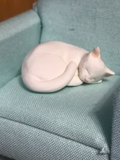 a white cat laying on top of a blue couch