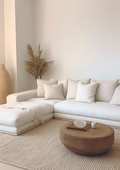 a living room with a large white couch and coffee table in front of the wall