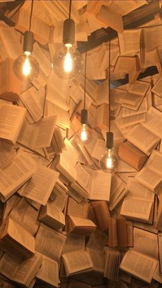 several light bulbs are hanging from the ceiling made out of book pages and bookshelves