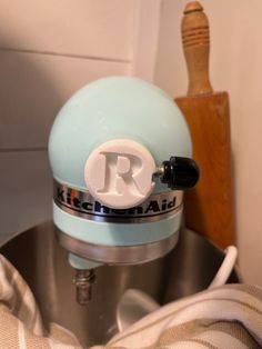 a kitchen aid mixer sitting on top of a metal bowl next to a wooden spatula