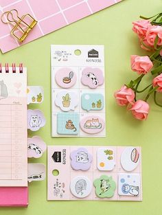 pink flowers and notebooks with stickers on them next to a notepad, pen and clipboard