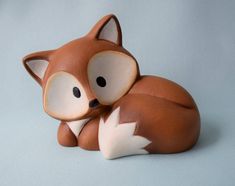 a ceramic fox figurine laying on top of a blue surface with its eyes closed