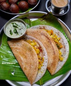 three pita breads on a plate next to some dipping sauce and green leaves