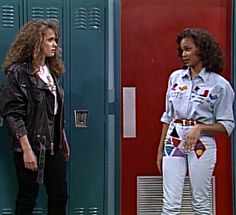 two women standing next to each other in front of lockers