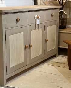 a kitchen cabinet with two doors and knobs on the front, next to a bench