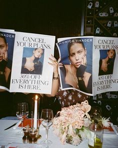 a table topped with posters and candles next to wine glasses on top of a table