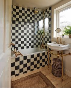 a bathroom with black and white tiles on the wall, sink and bathtub in it