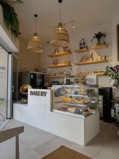 a bakery with lots of baked goods in the display case and hanging lights above it