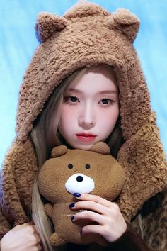 a girl in a bear costume holding a teddy bear with her face close to the camera