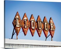 an old neon sign that says liquor on top of a building in front of a blue sky