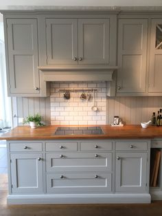 a kitchen with gray cabinets and wooden counter tops