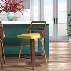 two wooden chairs sitting in front of a green counter top next to a potted plant