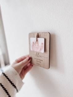 a person is holding up a wooden plaque on the wall