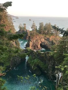 an aerial view of the ocean and cliffs near some trees in the foreground, with one person standing at the edge of the cliff