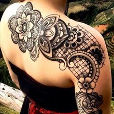 the back of a woman's shoulder with an intricate tattoo design on her arm