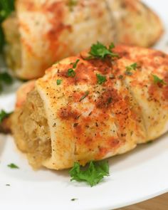 two pieces of food on a plate with parsley sprinkled around them and garnished with herbs