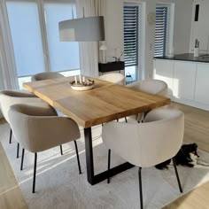 a dining room table with chairs and a dog laying on the floor in front of it