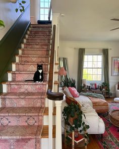 a black and white cat sitting on the stairs in a living room