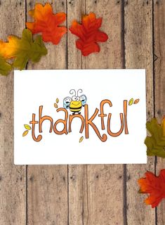 a card with the word thank written in orange and yellow leaves on it, surrounded by fall leaves