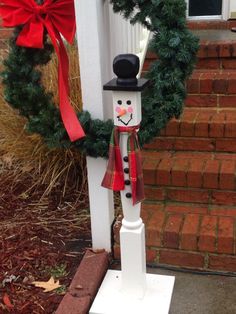 a snowman with a top hat and scarf on it's head is standing in front of a house