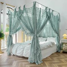 a canopy bed with sheer curtains on the top and bottom, sitting in a bedroom