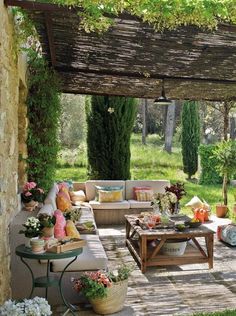 an outdoor living area with couches, tables and flowers on the table in front of it