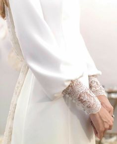 a close up of a person wearing a white dress and holding onto a handbag