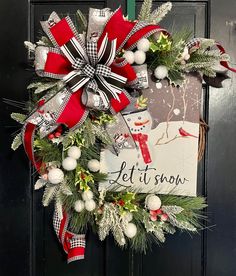 a christmas wreath hanging on the front door with an let it snow sign and decorations