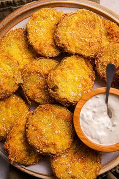 some fried food is on a plate with a small bowl of ranch dressing next to it