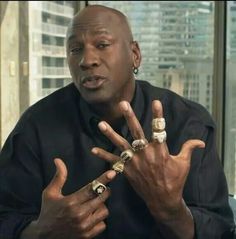 the man is holding his fingers up in front of him with two rings on each hand