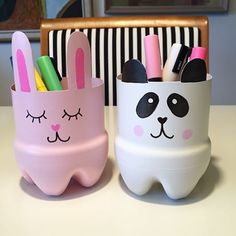 two white and pink pencil holders with faces painted on them, one is shaped like a bunny and the other has a panda face