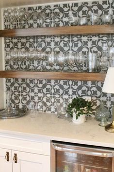 a kitchen with white cabinets and shelves filled with glasses on top of the cupboards