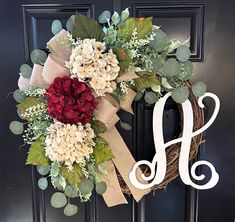 a front door wreath with the letter h on it and flowers hanging from it's side