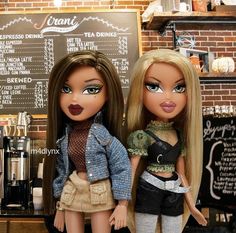 two dolls standing next to each other in front of a chalkboard with menus on it