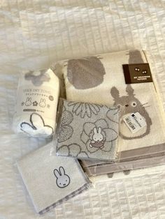 three towels and two napkins on a white bed with an animal design in the middle